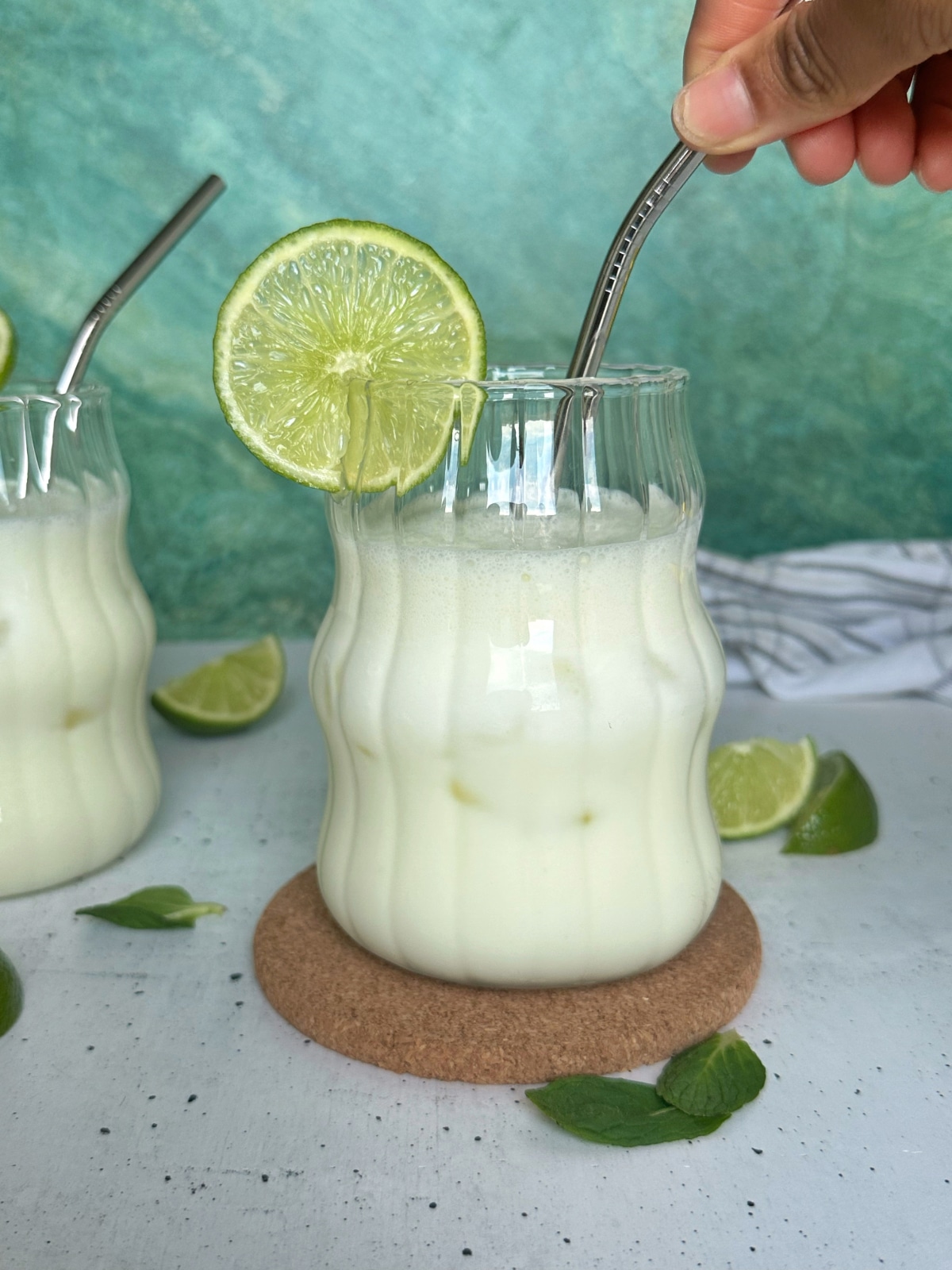 A hand stirring the straw in a glass of Brazilian limeade.