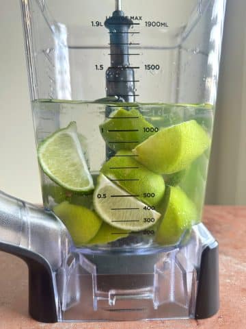 A blender of quartered limes in water.