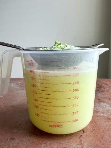 Blended limes being strained over a measuring cup.