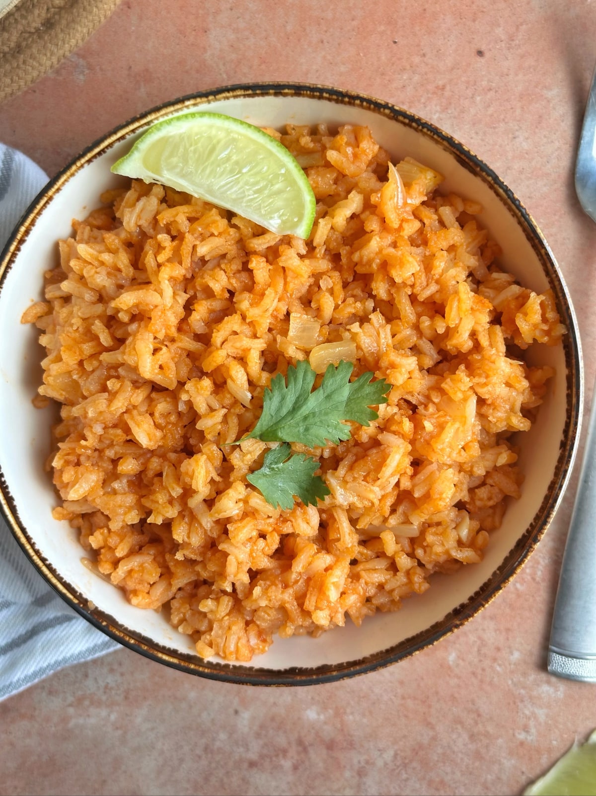 A bowl of arroz rojo or Mexican red rice with a lime wedge.