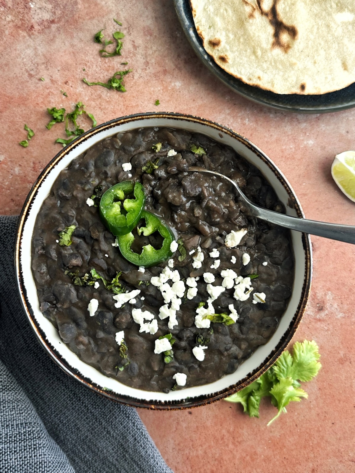 A bowl of refried frijoles negros with a spoon sticking out of it.