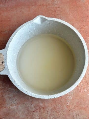 A cream-colored pot filled with sugar and water.