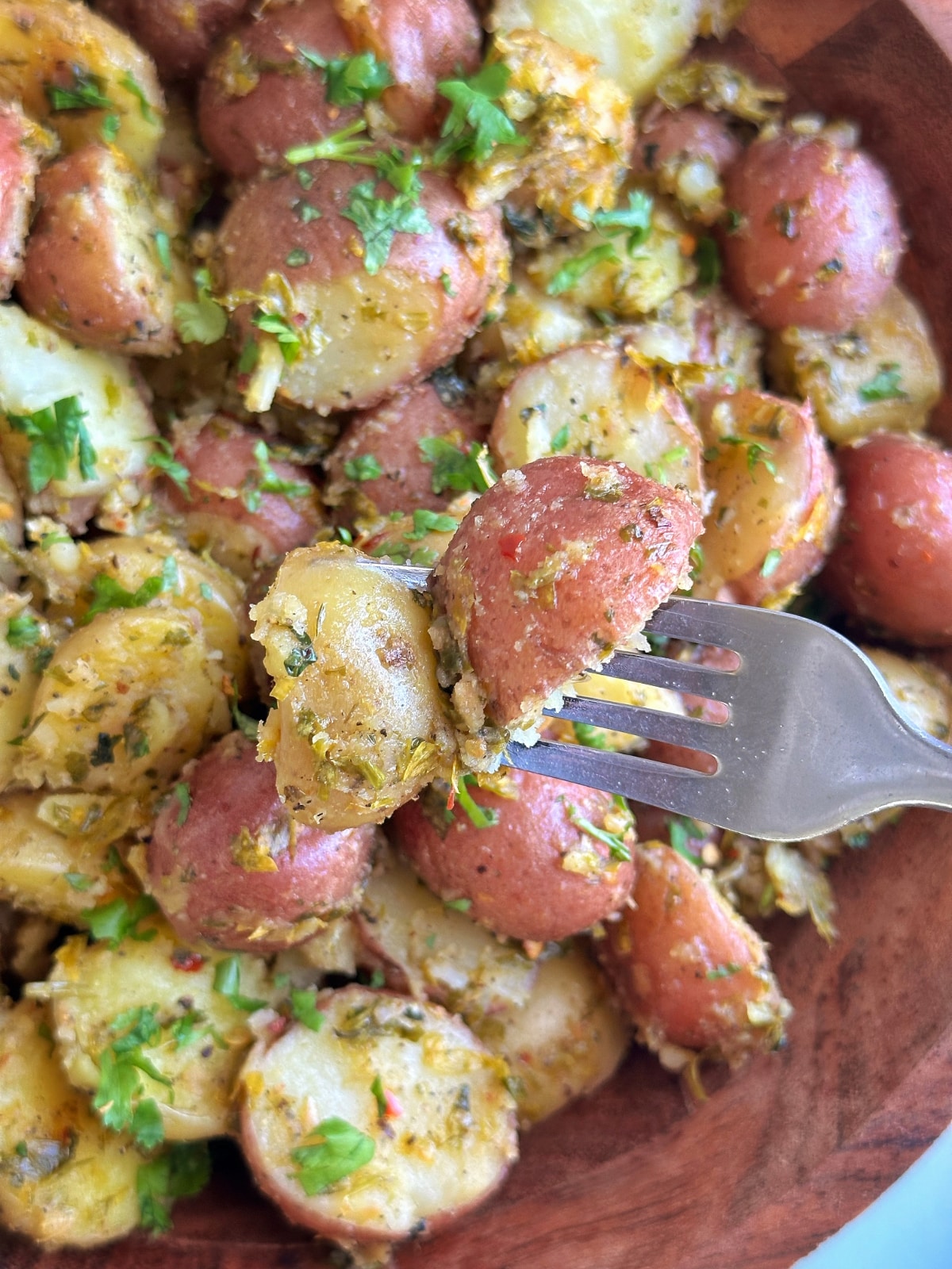 A fork holding up a bite of mayo-less potato salad with chimichurri.