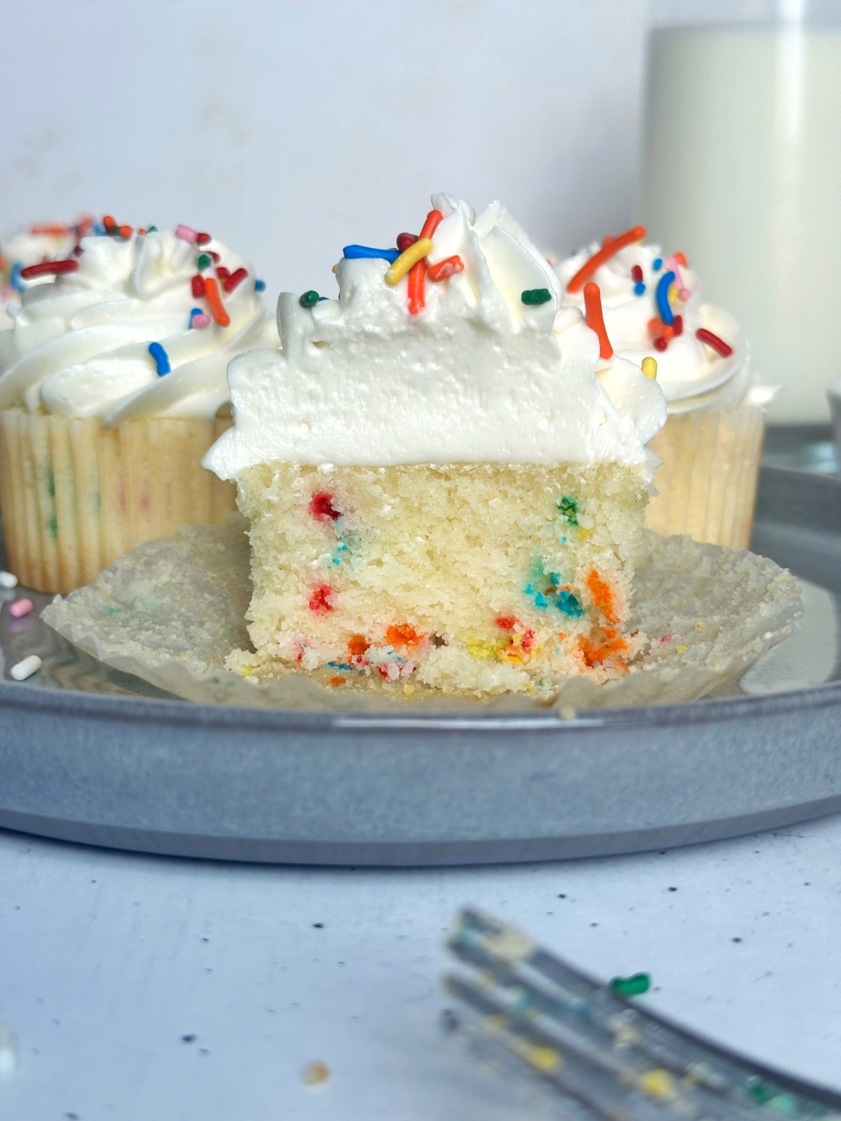 A funfetti cupcake split in half on a grey plate.