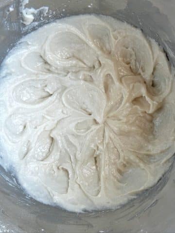 Vanilla cupcake batter in a silver mixing bowl.
