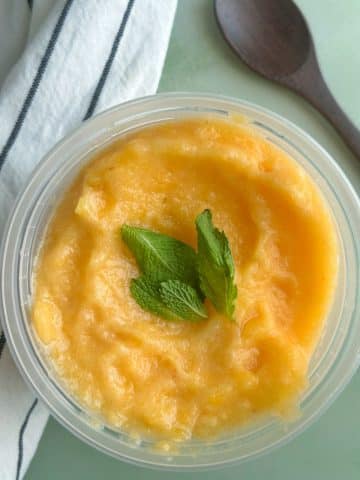A deli container filled with peach sorbet.