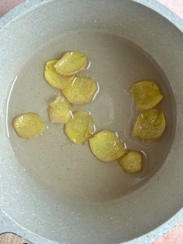 A saucepot with simple syrup and sliced ginger.