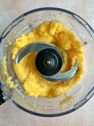 A food processor with peach sorbet inside.