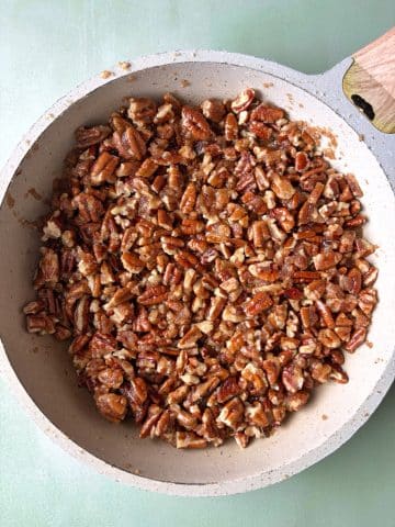 A skillet filled with homemade praline pecan pieces.