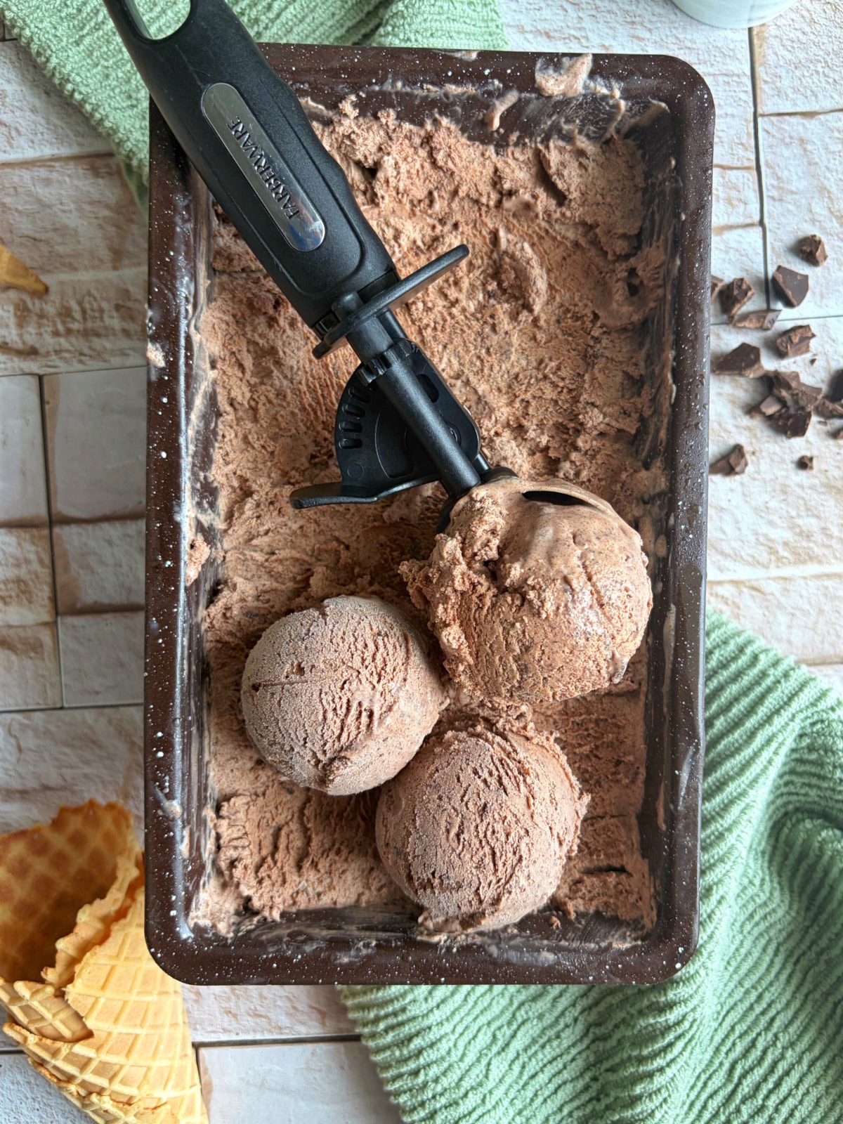 A pan of dark chocolate ice cream with scoops plopped on top.
