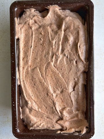 A loaf pan filled with dark chocolate ice cream base.