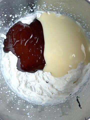A mixing bowl filled with whipped cream, condensed milk, and melted chocolate.