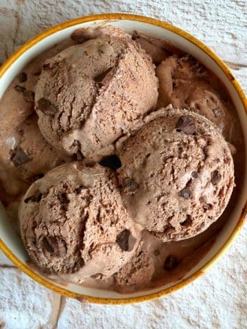 A bowl filled with scoops of dark chocolate ice cream.
