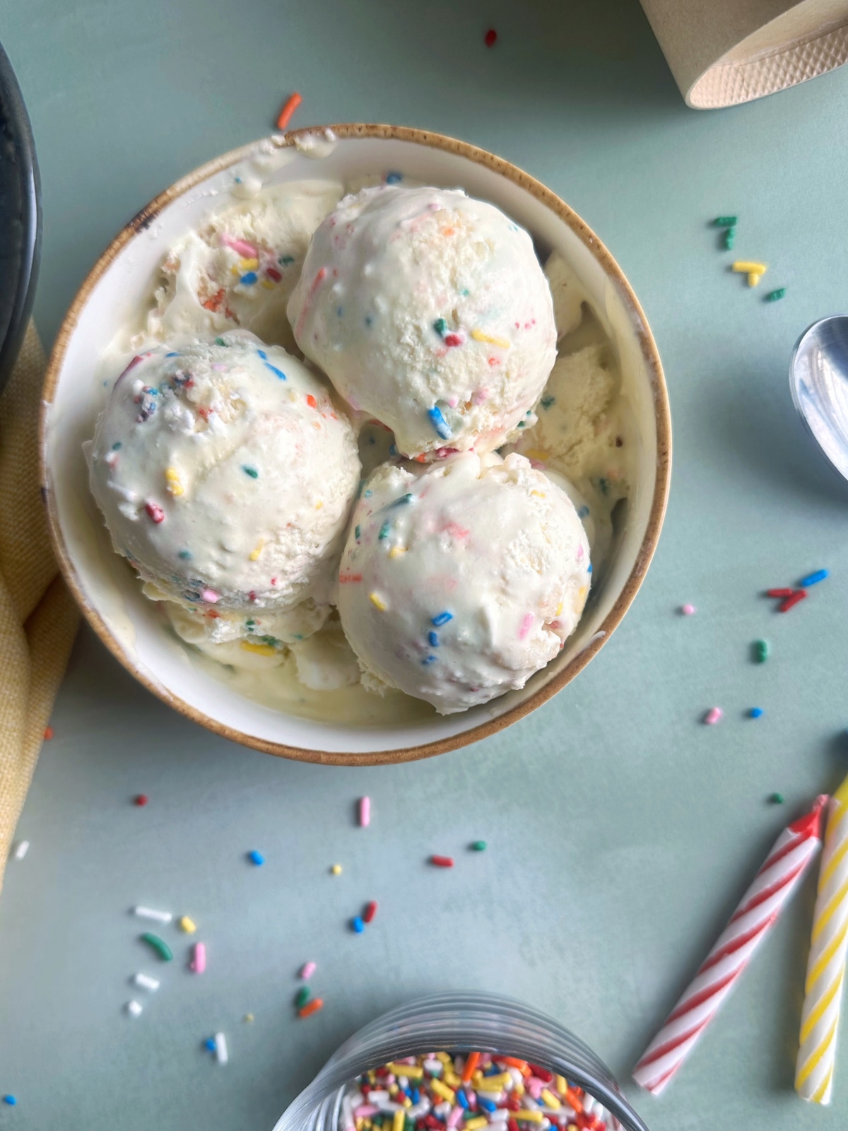 A bowl of funfetti ice cream with 3 scoops on top.