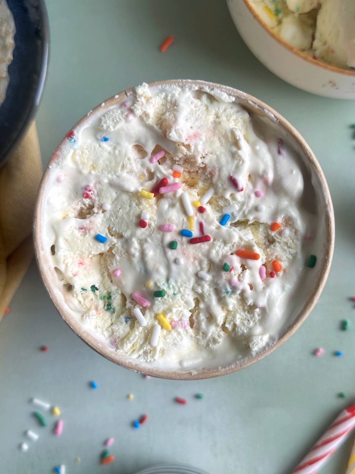 An ice cream pint container filled with vanilla ice cream with rainbow sprinkles.