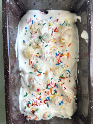 A loaf pan with funfetti ice cream and vanilla cake pieces inside.