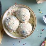 A bowl with three scoops of birthday cake funfetti ice cream inside.