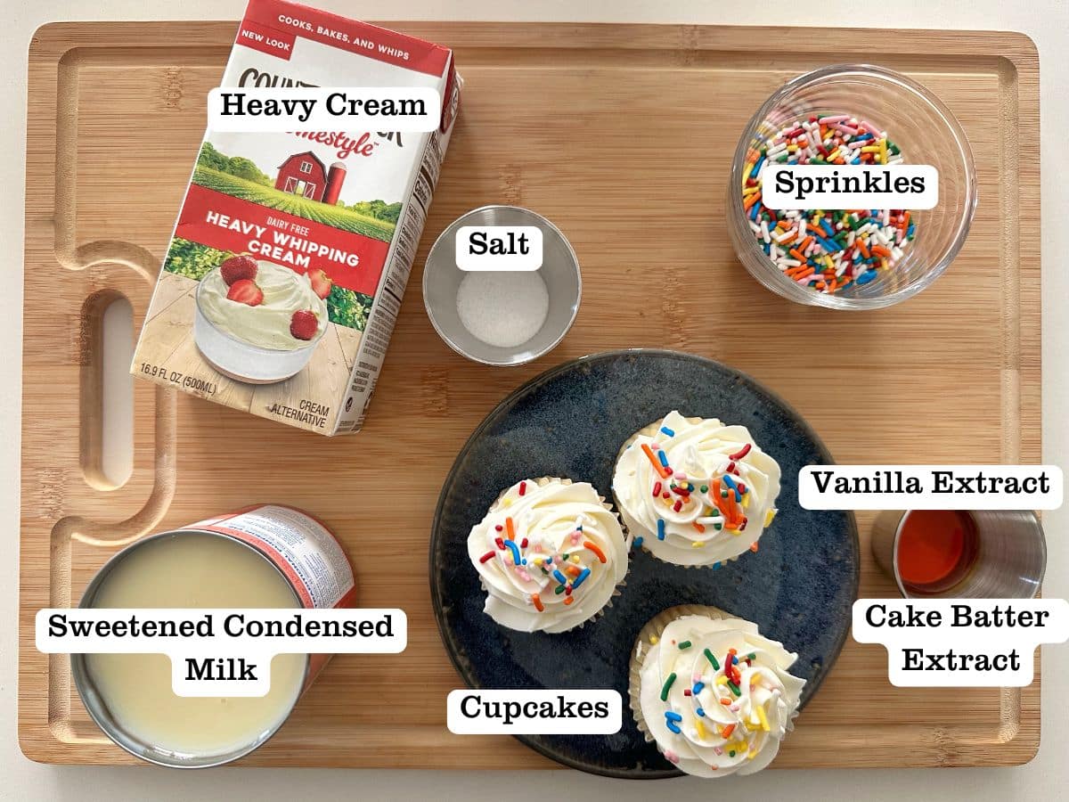 A wooden board with containers of ingredients for no-churn birthday cake ice cream.