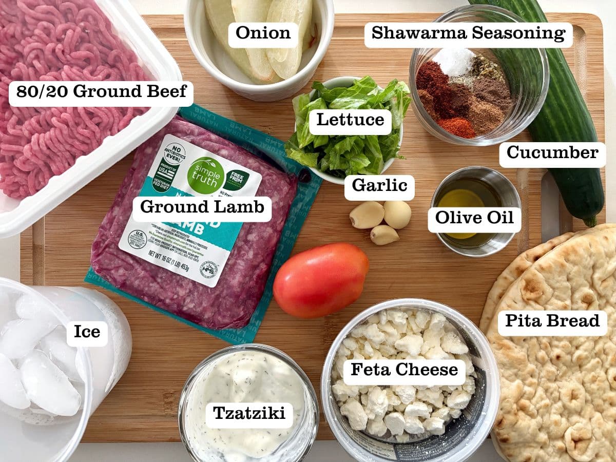 A wooden board filled with containers of ingredients to make lamb gyro wraps.