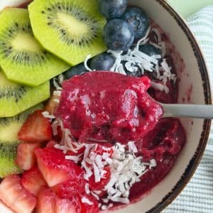 A spoon scooping up a bite of blueberry smoothie bowl.