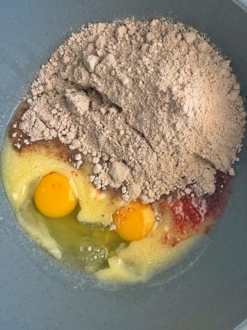 A mixing bowl with eggs, vanilla, melted butter, and cake mix.