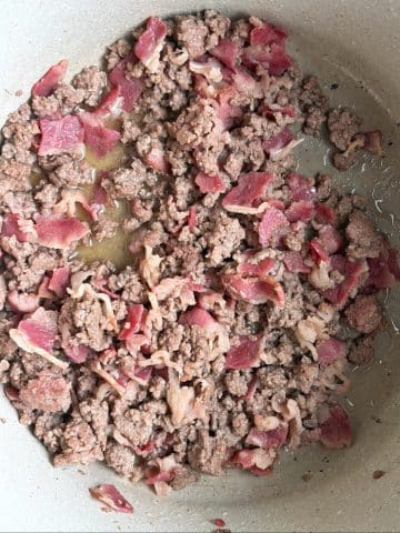 A pot of ground beef and bacon cooking down together.
