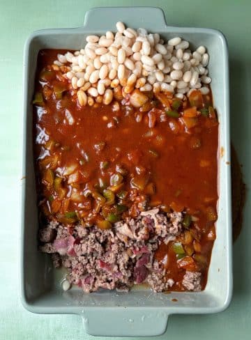 A baking pan with beans, barbecue sauce, and ground beef/bacon.