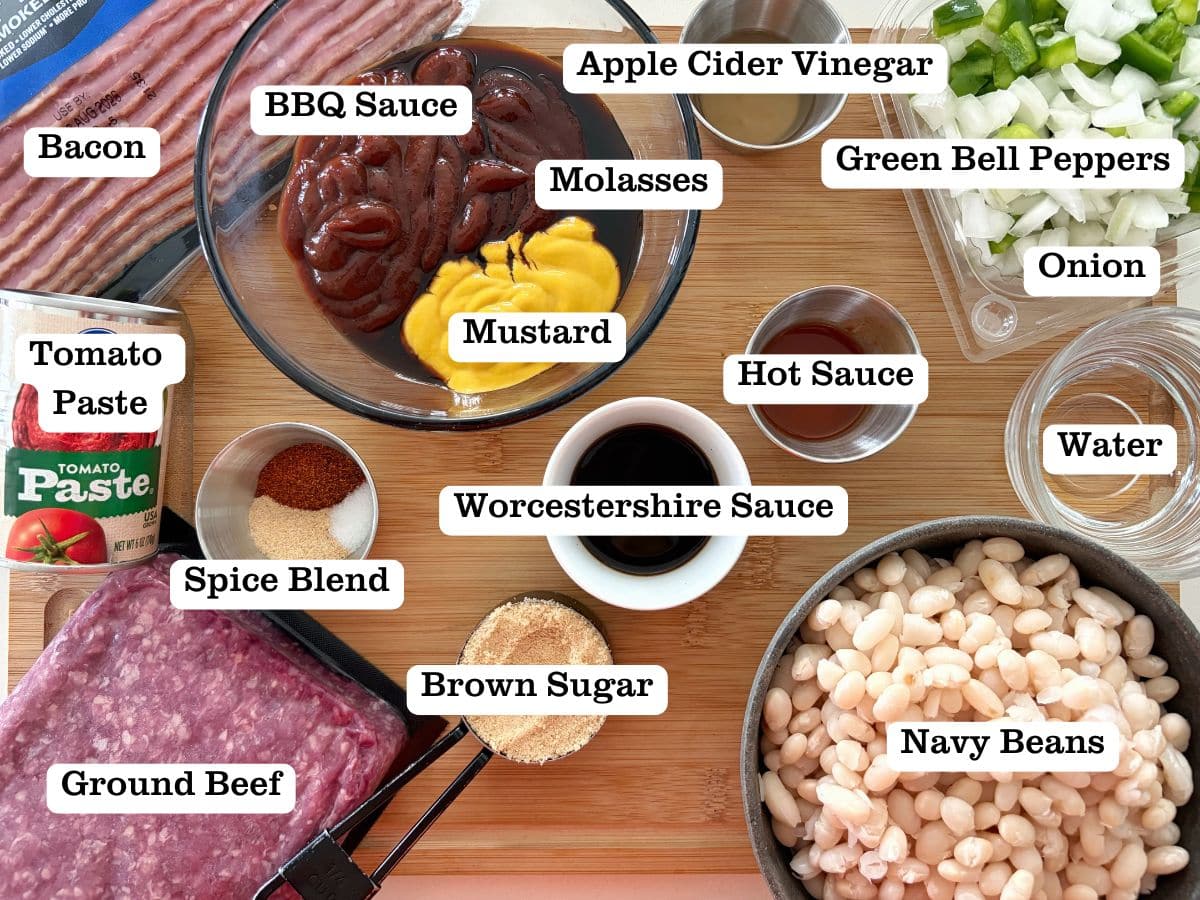 A wooden board with containers of ingredients for homemade baked beans, including navy beans and Worcestershire.
