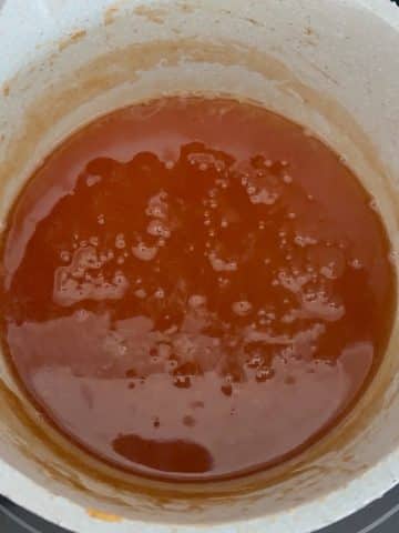 A saucepot filled with apple cider, reduced to a syrup.