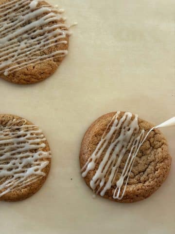 A cookie being drizzled with a white apple-flavored glaze.