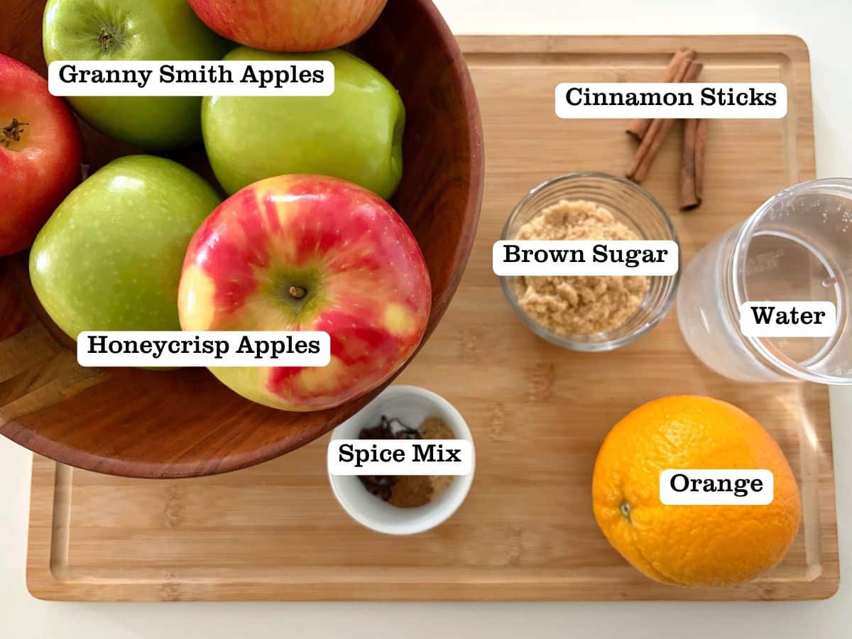 A wooden board with containers of ingredients to make apple cider.
