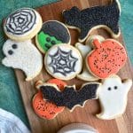 A wooden tray with lots of royal icing-decorated sugar cookies shaped like Halloween designs.