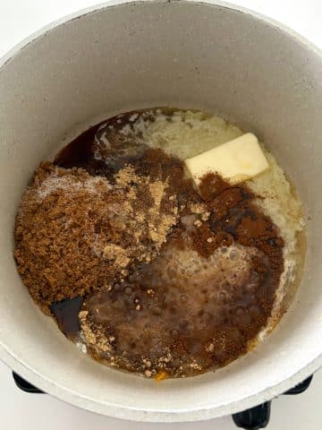 A pot filled with melting butter, sugars, spices, and orange juice.