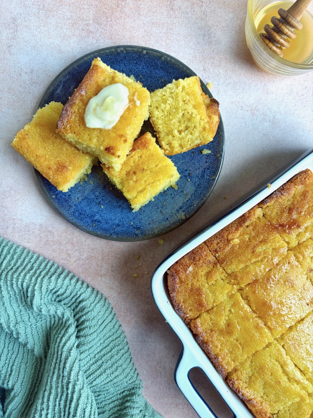 A plate of honey butter cornbread stacked on each other, with the rest of the baking pan in the corner of the photo.
