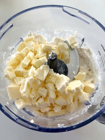 Cold butter cubes, flour, salt, and sugar in a food processor bowl.
