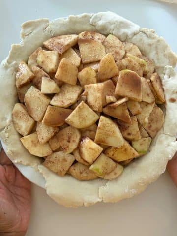 Seasoned apple slices in a pie dough-lined pie plate