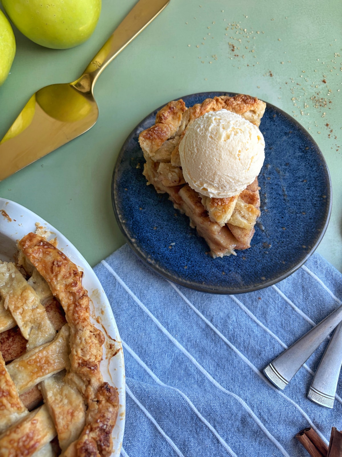 A slice of apple pie with ice cream on top on a blue plate.