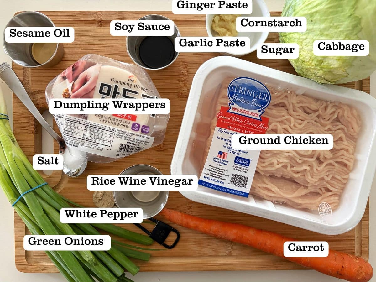 A board with containers of ingredients to make steamed Asian dumplings with ground chicken.