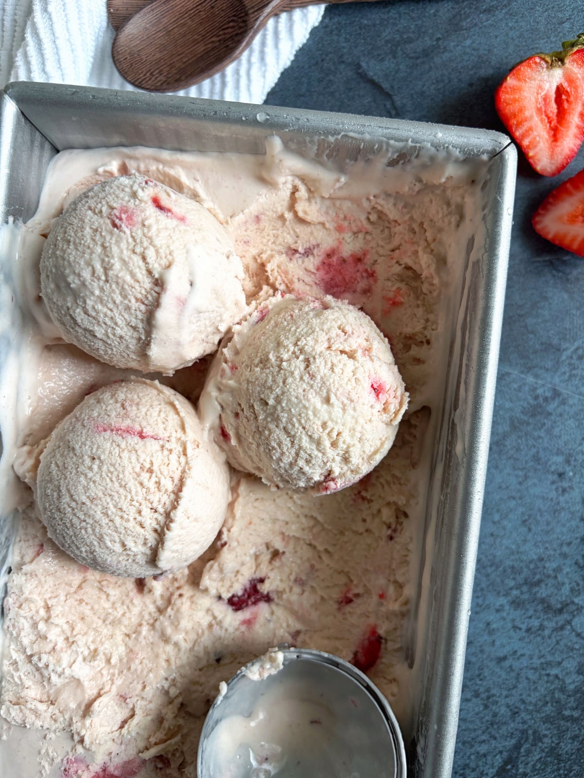 A loaf pan with three scoops of no-churn strawberry ice cream in the corner.