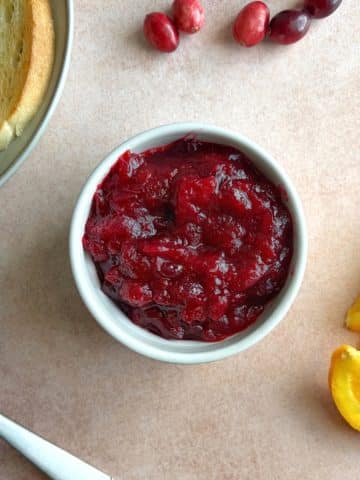 A bowl of cranberry orange jam with containers of toast and other ingredients on the side.