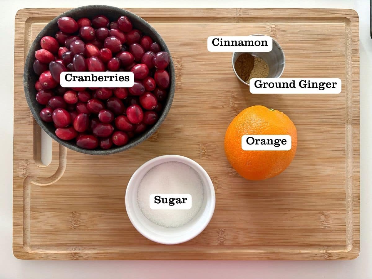 A board with containers of ingredients to make orange cranberry preserves.