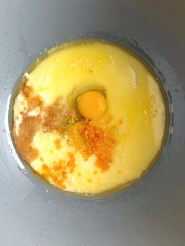 A mixing bowl with eggs, buttermilk, melted butter, and orange zest.