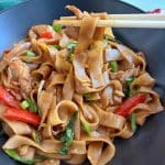 A bowl of pad kee Mao, or drunken noodles, with a pair of chopsticks picking up a bite.