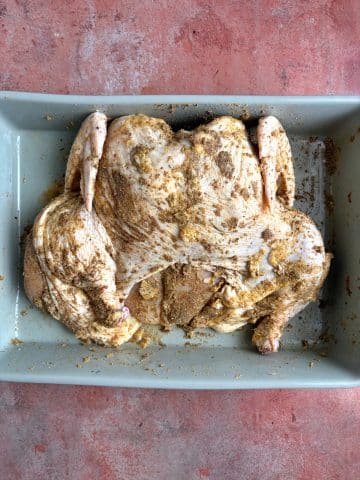 A seasoned spatchcock chicken before being roasted in the oven.