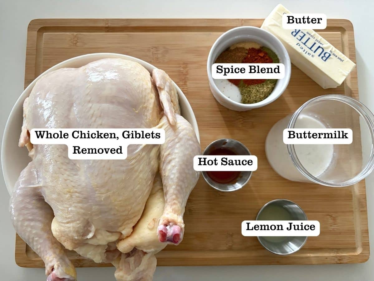 A wooden board with ingredients to make spatchcocked chicken in the oven.